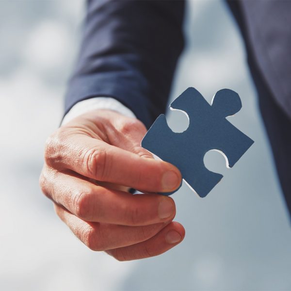 Closeup of hand with jigsaw puzzle. Sky background.